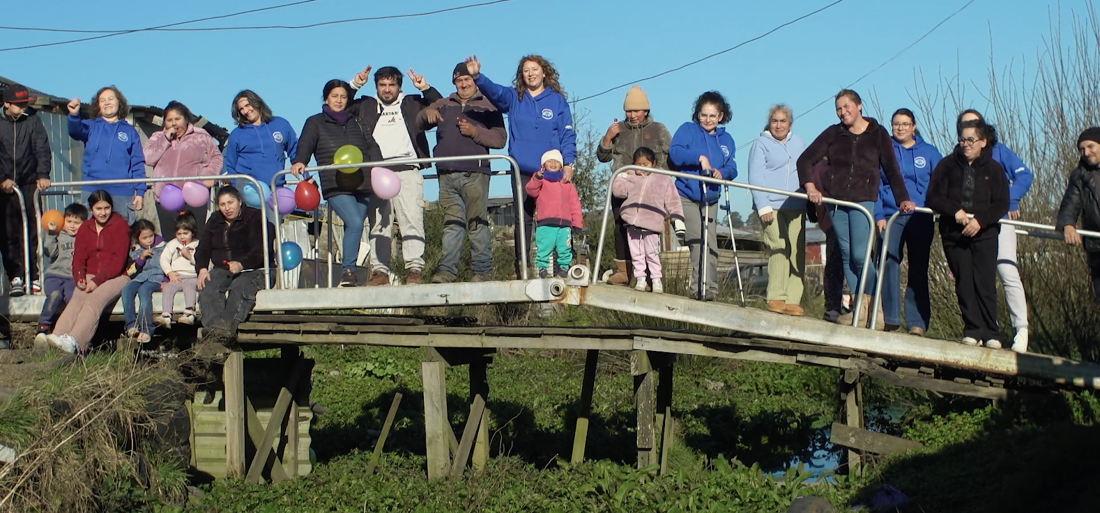 Vecinos y voluntarios sobre una pasarela en Nuevo Amanecer, documental de Cooke Chile